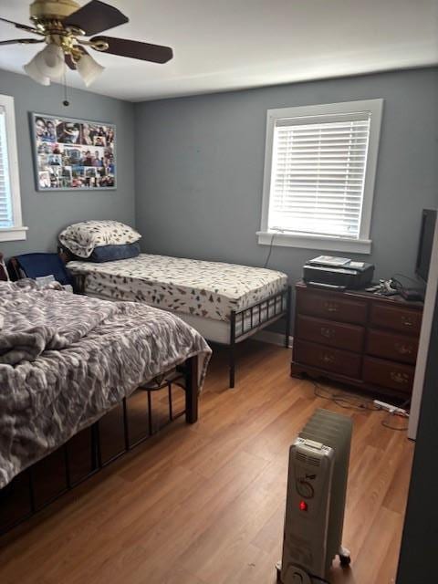 bedroom with multiple windows, light wood-type flooring, and a ceiling fan