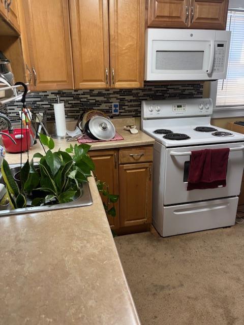 kitchen featuring brown cabinetry, white appliances, light countertops, and decorative backsplash