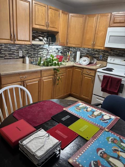 kitchen featuring white appliances, backsplash, a sink, and light countertops