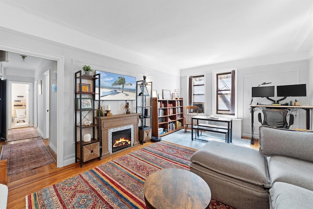 living room with a warm lit fireplace, baseboards, and wood finished floors