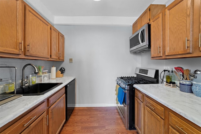 kitchen with a sink, baseboards, appliances with stainless steel finishes, backsplash, and dark wood-style floors