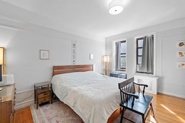 bedroom with radiator heating unit, baseboards, and wood finished floors