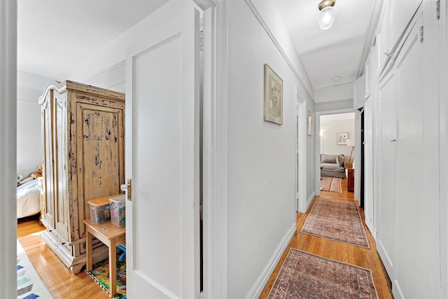 corridor featuring baseboards and light wood-style floors