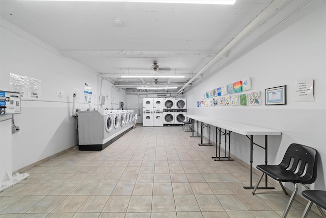 misc room with a garage, light tile patterned floors, baseboards, stacked washer / drying machine, and washing machine and dryer