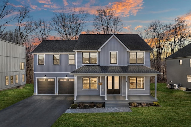 view of front facade with a front lawn, aphalt driveway, covered porch, a shingled roof, and a garage