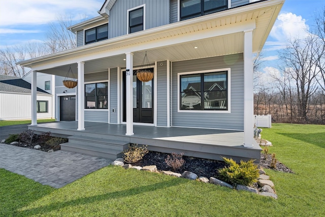 view of exterior entry featuring board and batten siding, a yard, covered porch, and driveway