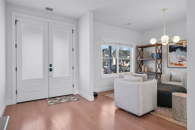 foyer entrance with baseboards, visible vents, a chandelier, and light wood-type flooring