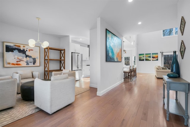 living room with recessed lighting, light wood-type flooring, baseboards, and a chandelier