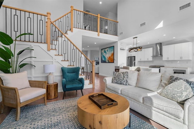 living area featuring stairway, wood finished floors, visible vents, and baseboards