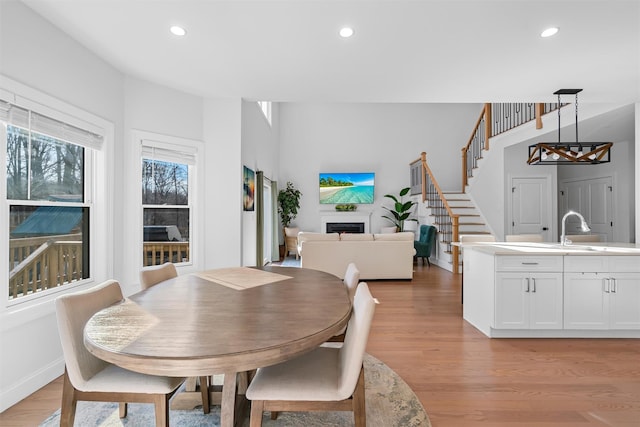 dining area with light wood finished floors, baseboards, stairs, recessed lighting, and a fireplace