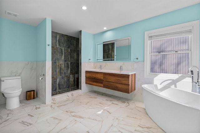 bathroom featuring double vanity, recessed lighting, a soaking tub, marble finish floor, and tile walls