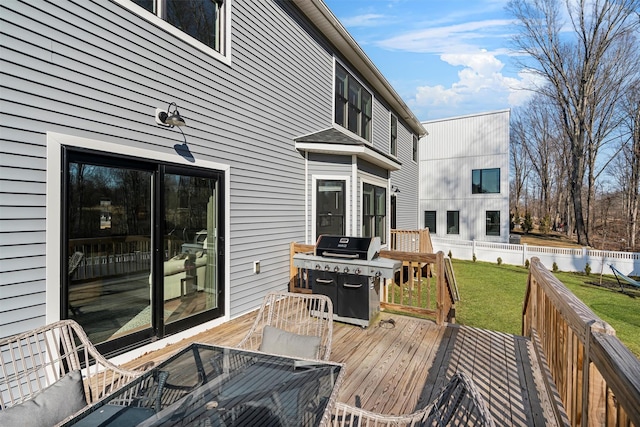 wooden terrace featuring grilling area, a lawn, and fence