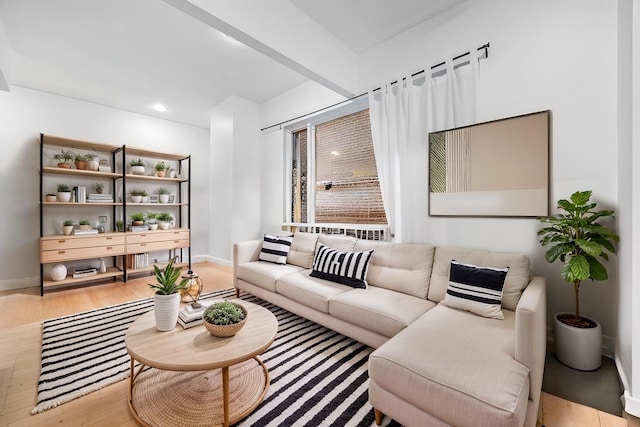 living room featuring light wood finished floors, beam ceiling, and baseboards