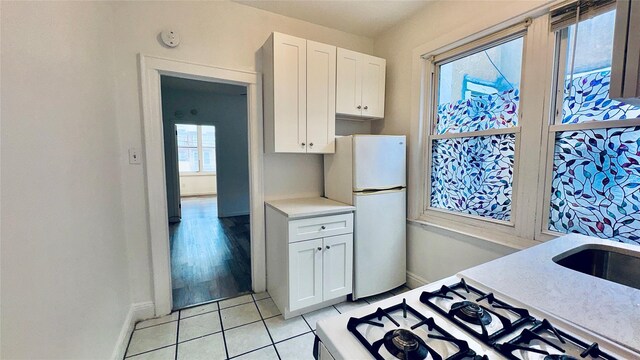 10634 Sutphin Blvd, Jamaica, NY 11435 - kitchen featuring baseboards, light countertops, freestanding refrigerator, white cabinetry, and light tile patterned flooring