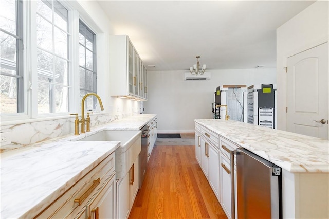 kitchen featuring light stone counters, light wood-style flooring, white cabinets, a wall mounted AC, and glass insert cabinets