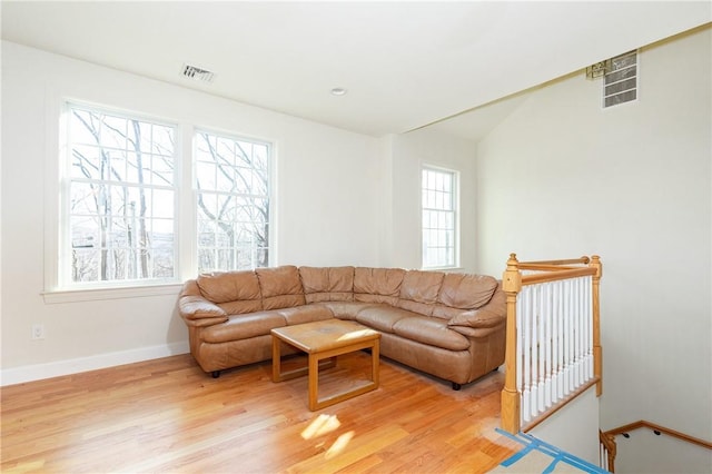 living room featuring light wood finished floors, baseboards, and visible vents