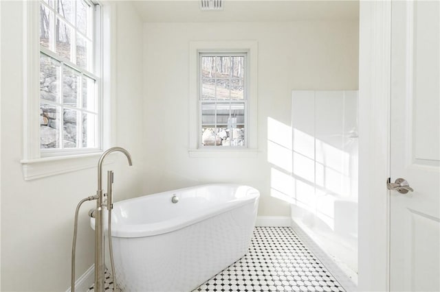 bathroom featuring visible vents, a freestanding bath, baseboards, and tile patterned floors