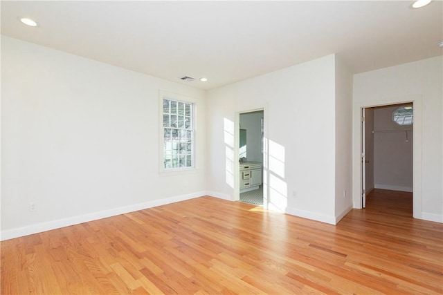 unfurnished bedroom with light wood-type flooring, baseboards, a walk in closet, and recessed lighting