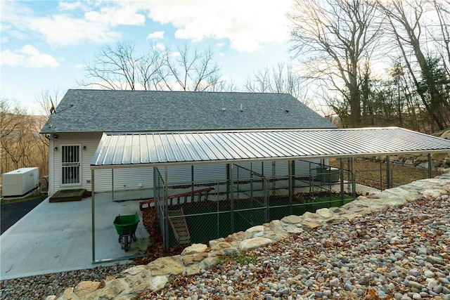 back of property featuring central air condition unit, a patio area, metal roof, and roof with shingles