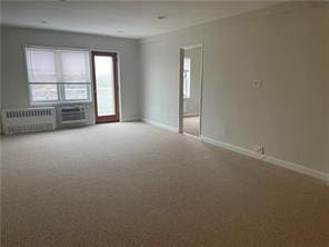 unfurnished room with radiator, carpet floors, and baseboards