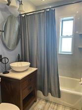 full bath with toilet, wood finished floors, shower / bath combo with shower curtain, and vanity