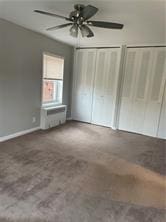 unfurnished bedroom with a ceiling fan and two closets