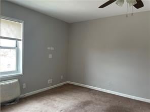 carpeted spare room with baseboards and a ceiling fan