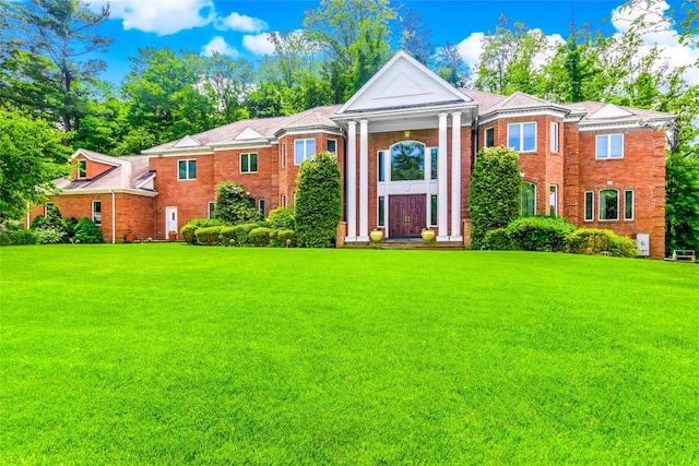 greek revival house featuring brick siding and a front yard