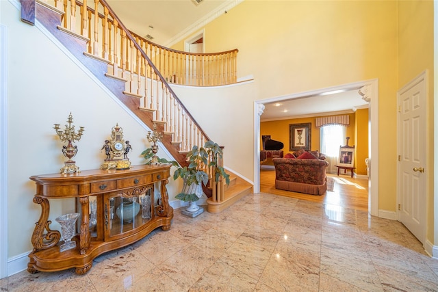 entrance foyer featuring ornamental molding, stairway, a towering ceiling, and baseboards