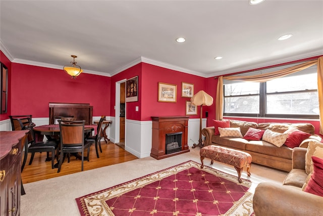 carpeted living area featuring a fireplace, ornamental molding, recessed lighting, and wainscoting