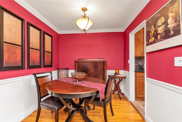 dining room with light wood-type flooring and ornamental molding