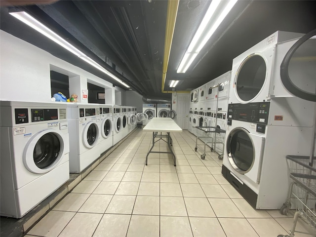 community laundry room featuring washer and clothes dryer, light tile patterned floors, and stacked washer / drying machine