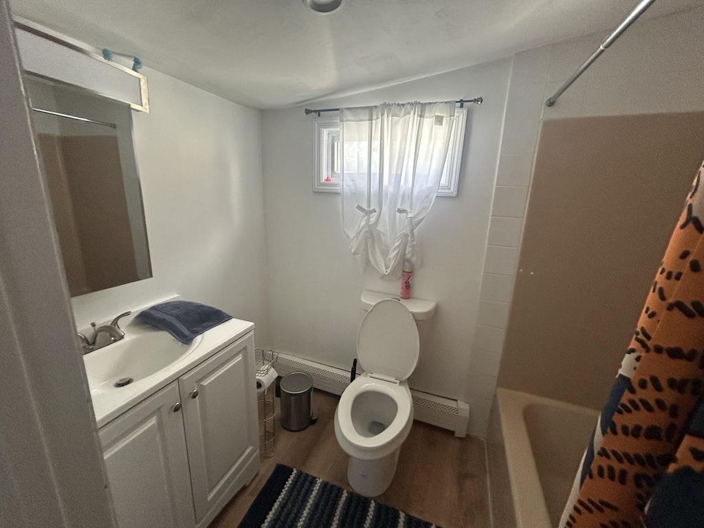 bathroom featuring toilet, a baseboard heating unit, wood finished floors, and vanity