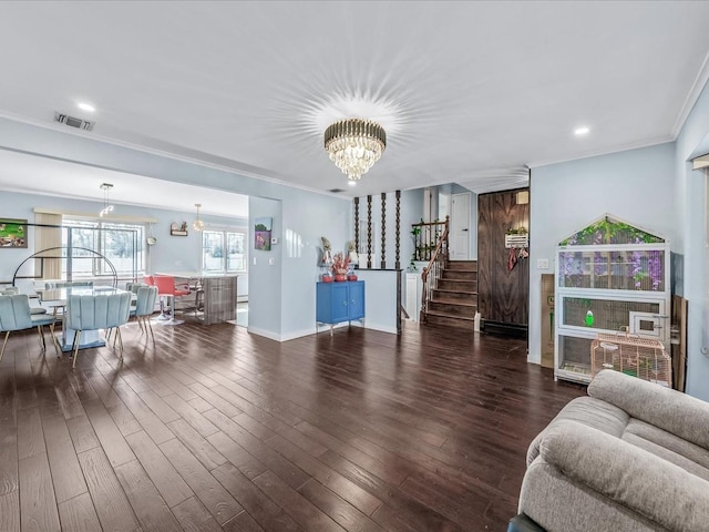 living room featuring a chandelier, wood finished floors, visible vents, stairway, and crown molding