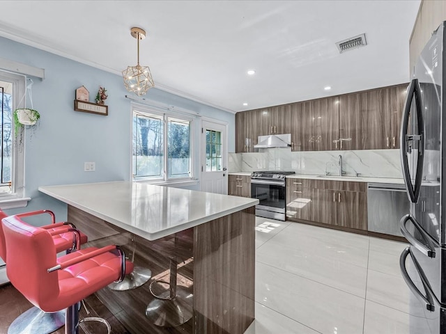 kitchen with stainless steel appliances, light countertops, backsplash, modern cabinets, and extractor fan