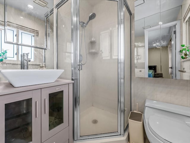 ensuite bathroom featuring a shower stall, backsplash, and tile walls