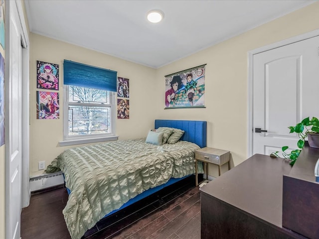 bedroom with a baseboard heating unit and dark wood-style flooring