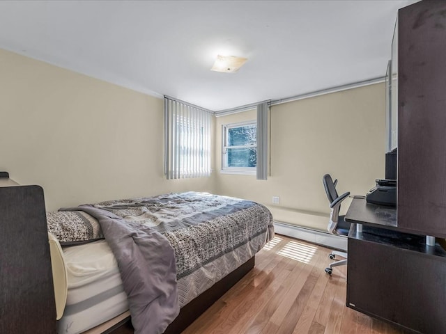 bedroom with a baseboard heating unit and wood finished floors