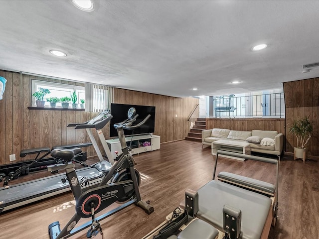 exercise room with wooden walls, visible vents, wood finished floors, and recessed lighting