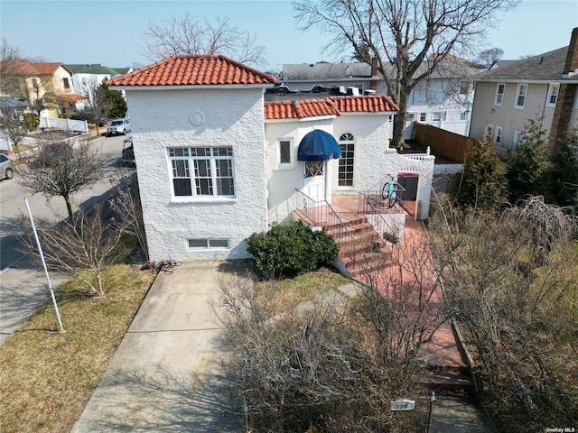 view of front of home with fence, a tile roof, and stucco siding