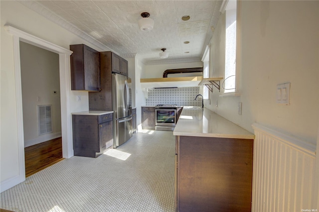 kitchen with dark brown cabinetry, visible vents, appliances with stainless steel finishes, light countertops, and a sink
