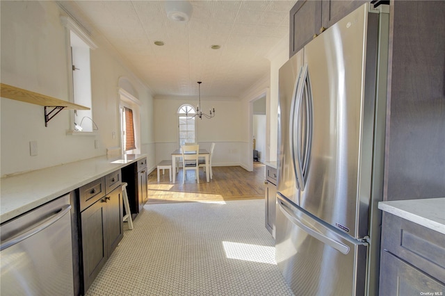 kitchen featuring appliances with stainless steel finishes, ornamental molding, hanging light fixtures, an inviting chandelier, and dark brown cabinets