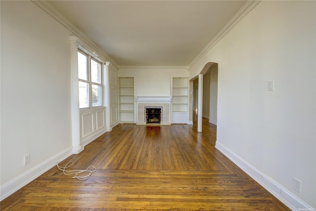 unfurnished living room with arched walkways, dark wood-type flooring, a fireplace with flush hearth, baseboards, and ornamental molding