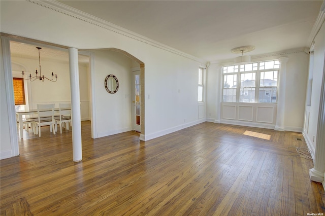 unfurnished living room with baseboards, arched walkways, hardwood / wood-style flooring, an inviting chandelier, and crown molding