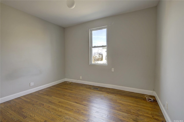 spare room featuring visible vents, baseboards, and wood finished floors