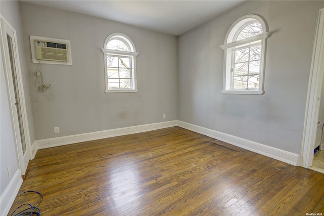 empty room with plenty of natural light, baseboards, and wood finished floors
