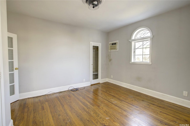 spare room with a wall mounted AC, wood finished floors, and baseboards