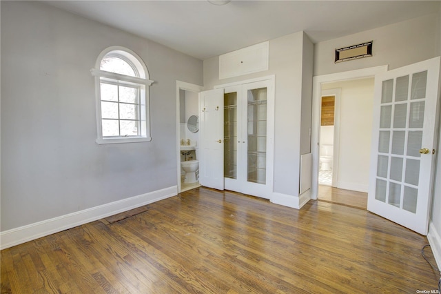 spare room featuring french doors, wood finished floors, and baseboards