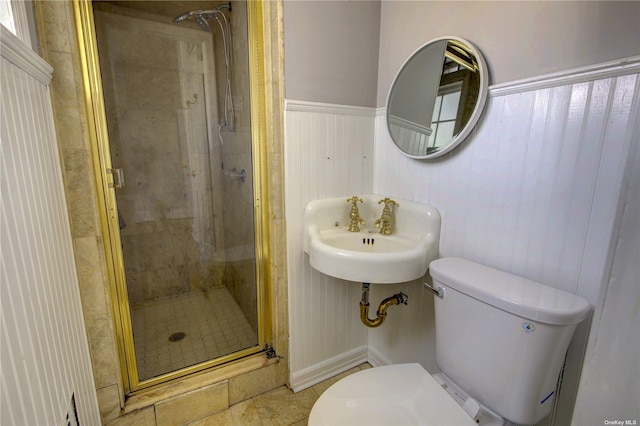 bathroom featuring a stall shower, wainscoting, a sink, and toilet