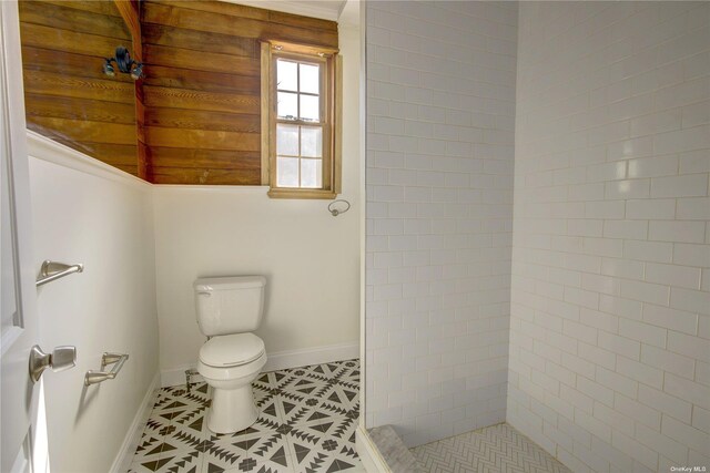 full bathroom featuring baseboards, a tile shower, toilet, and tile patterned floors
